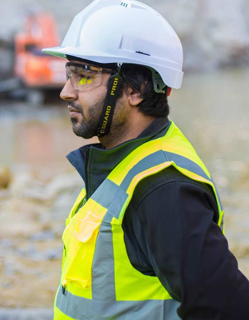 Man Using Measuring Tape in Factory Setting Man Using Measuring Tape in Factory Setting